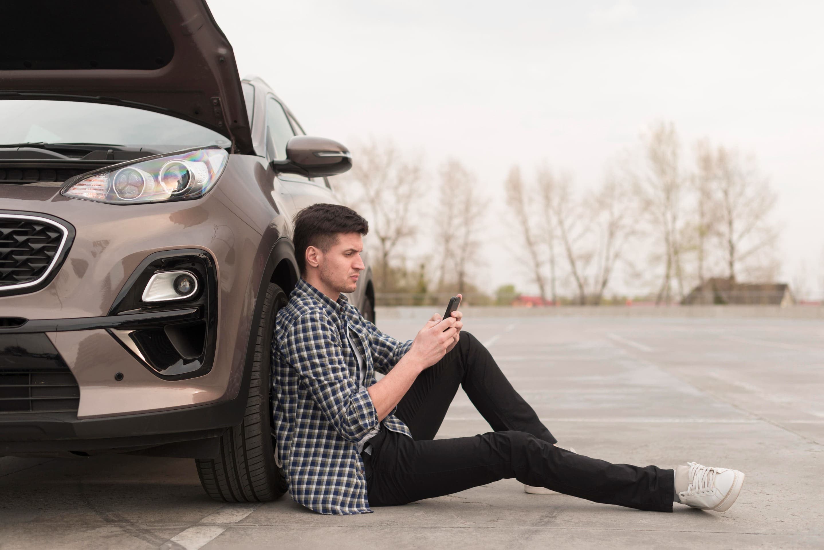 Vista lateral de um homem sentado ao lado de um carro